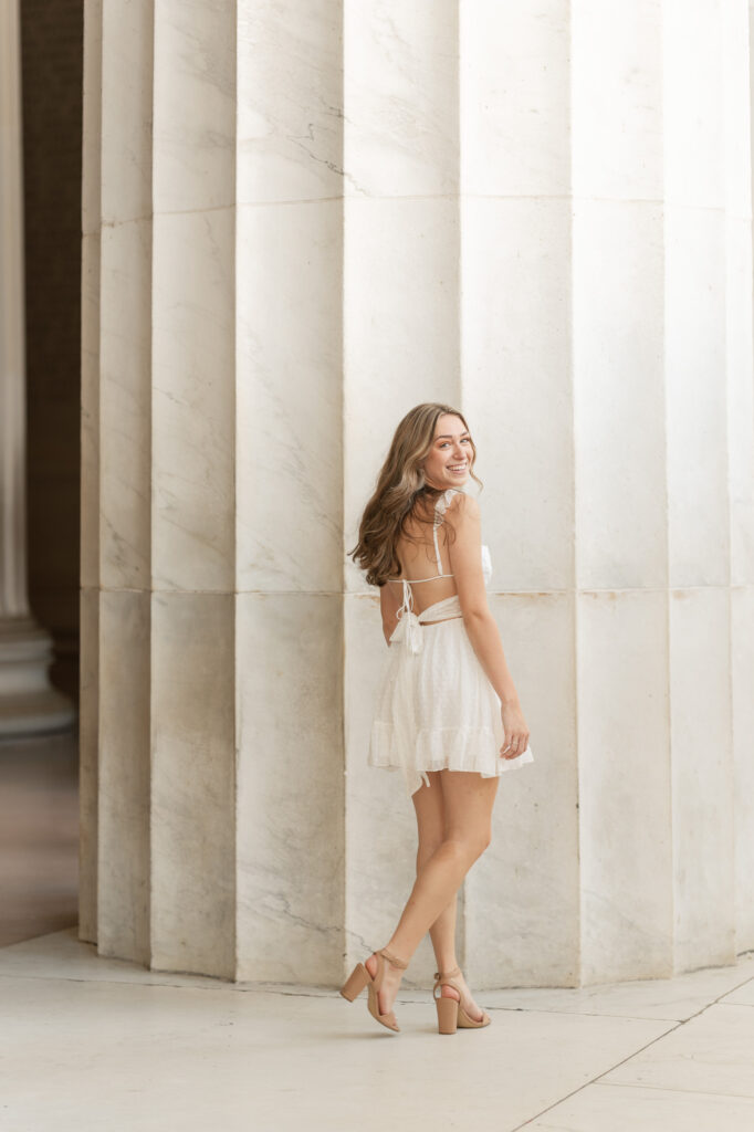 high school girl posing for her senior portraits at the lincoln memorial in washington d.c.
